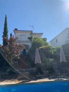 a house with two umbrellas and a swimming pool at Casa con encanto en Monachil in Monachil