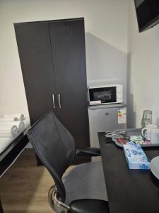 a black chair sitting next to a table with a microwave at Comfort Lodge in Nottingham
