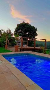 a blue swimming pool in front of a gazebo at Chácara Pôr do sol in Alfenas