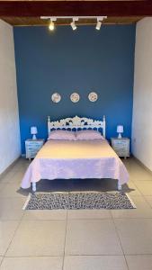 a bedroom with a bed with a blue wall at Chácara Pôr do sol in Alfenas
