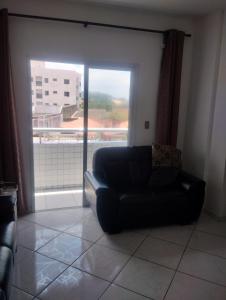 a black couch in a living room with a window at Apto mongagua in Mongaguá +7 photos