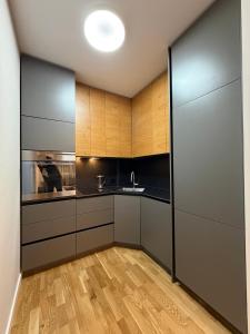 a kitchen with gray cabinets and a wooden floor at ZONE apartments in Prishtinë