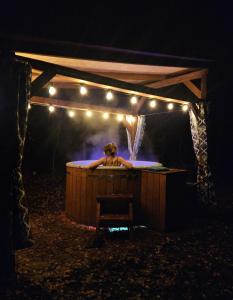 a woman in a hot tub with lights on it at Jurty i namioty w Lesie KotfaLas Glamping Świętokrzyskie-SPA in Skarżysko-Kamienna