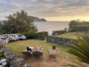 two people sitting in chairs on the grass near the water at Quintinha da Chinela in Porto Judeu