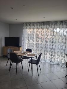 a dining room with two tables and chairs and a television at Duplex avec Parking in Chassieu
