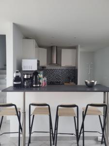 a kitchen with a counter with four stools at Duplex avec Parking in Chassieu