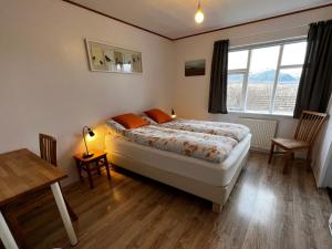 a bedroom with a bed and a table and a window at Sudur-Bár Guesthouse in Grundarfjordur