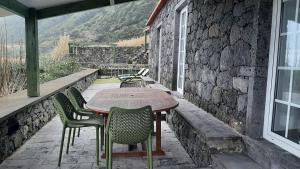 a table and chairs on a patio with a stone wall at Casas de Brisa in Calheta