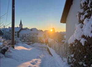 a snowy street with a fence and a church at Gemütliche 3 Zimmerwohnung in Ühlingen-Birkendorf