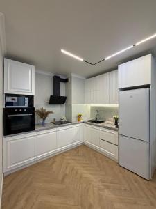 a large kitchen with white cabinets and a refrigerator at Walk Everywhere & Tourist Pick & Центр Города Алматы in Almaty +15 photos