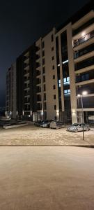 a parking lot in front of a building at night at ZONE apartments in Prishtinë