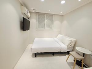 a white room with a bed and a chair at Han River KS Stay in Seoul