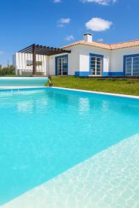 a large swimming pool in front of a house at Quinta Maria Cotovia in Porto Covo