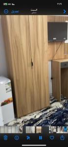 a kitchen with a wooden cupboard and a microwave at فندق اوتاد المتحدة المعابدة in An Naqāʼ