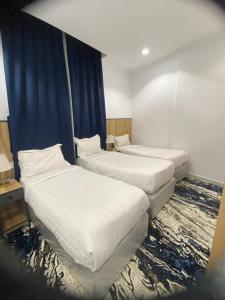 two beds in a hotel room with blue curtains at فندق اوتاد المتحدة المعابدة in An Naqāʼ +19 photos