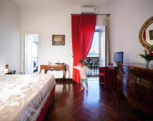 a little boy standing in a bedroom with a red curtain at B&B Dumbolo in Pozzuoli