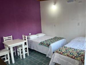 a room with two beds and a table and a table and chairs at Monoambiente Noah in Ezeiza