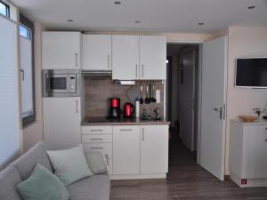 a kitchen with white cabinets and a couch in a room at Hausboot Paula mit Reisekajak in Ribnitz-Damgarten in Ribnitz-Damgarten