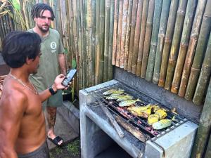a man is standing next to a grill at The middle Surf house in Airsatang