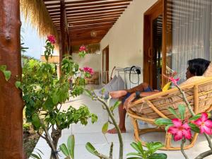 a woman sitting in a wicker chair on a porch at The middle Surf house in Airsatang