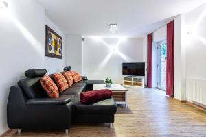 a living room with a black leather couch and a tv at Ferienwohnungen Ammerwinkel in Oberammergau