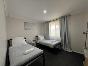 two beds in a small room with a window at Southern Comfort in Esperance in Esperance +4 photos