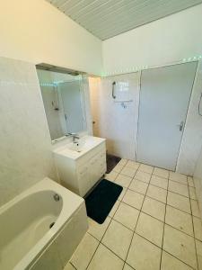 a bathroom with a tub and a sink and a shower at Sermie T4 à kourou avec piscine in Kourou +25 photos