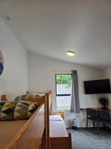 a bedroom with a bed and a desk and a television at Tasman Holiday Parks - Coromandel in Coromandel Town