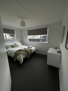 a bedroom with a large bed and two windows at Relax at Jollie-Cozy 3-Bedroom Home, Central Twizel in Twizel