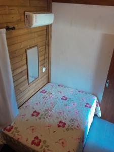 a small bedroom with a bed with a floral comforter at ResidencialBambu2 in Garopaba