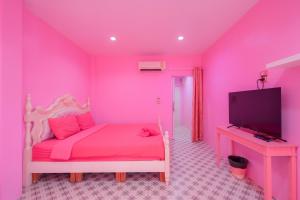 a pink room with a bed and a tv at บ้านพวงชมพูเกาะล้าน in Ko Larn