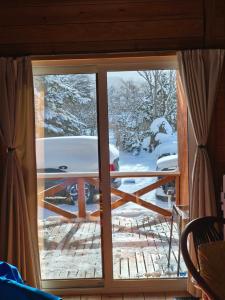 a sliding glass door with a view of a snow covered yard at 源泉ログの宿 in Sobetsu