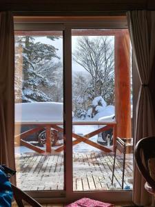 a view of a snow covered yard from a window at 源泉ログの宿 in Sobetsu