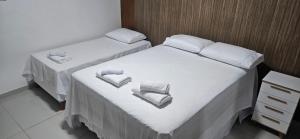 two beds in a room with white sheets and towels at Residencial Carmo&Costa in Belém