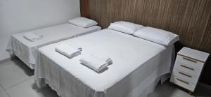 two beds in a room with white sheets and towels at Residencial Carmo&Costa in Belém