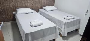 two beds in a room with white sheets and towels at Residencial Carmo&Costa in Belém