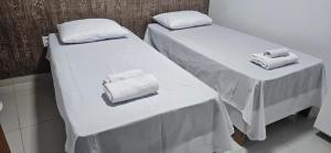 two beds in a room with towels on them at Residencial Carmo&Costa in Belém