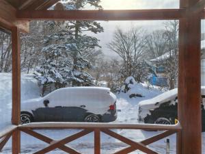 a snow covered car parked in a yard at 源泉ログの宿 in Sobetsu