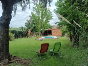 two chairs sitting in the grass next to a pool at Casa Darragueira de Chacras de Coria in Chacras de Coria