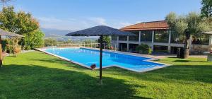a swimming pool with an umbrella next to a house at Quinta da Raiz in Canedo de Basto +21 photos