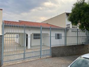 a fence in front of a white building at Seu refúgio com três quartos e garagem gigante in Indaiatuba