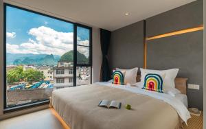a bedroom with a large bed with a large window at Yangshuo MUSE Mountain View Retreat in Guilin +102 photos