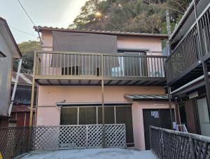 a pink house with a balcony and a garage at 伊豆の宿 静川 in Ito
