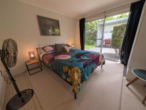 a bedroom with a bed and a fan and a window at Rainforest Cottage in Port Macquarie +48 photos