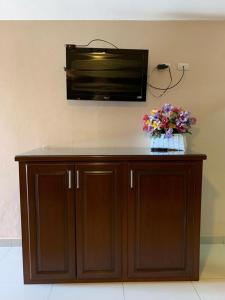 a wooden cabinet with a tv on the wall with flowers on it at Suites Posada Obregon in Ciudad Obregón