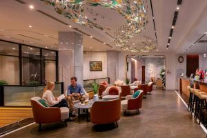 a lobby of a hotel with people sitting at tables at GRAND CITITEL Hanoi Hotel & Spa in Hanoi