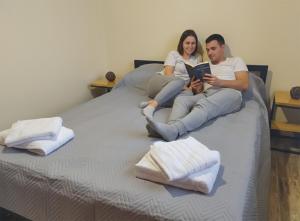 a man and woman sitting on a bed reading a book at Cabañas Ventalia in El Calafate