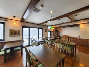 a dining room with tables and chairs and windows at ドッグランがある宿-ペンション歩野慕野-honobono in Kitashiobara