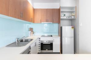 a kitchen with a sink and a refrigerator at Comfortable Loft Living in Footscray in Melbourne