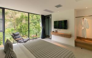 a bedroom with a bed and a tv and a chair at Yangshuo MUSE Mountain View Retreat in Guilin